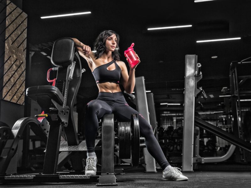 The girl is resting after fitness classes in the gym on a dark background.